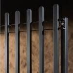 Un primo piano di una recinzione metallica con un muro di legno sullo sfondo.