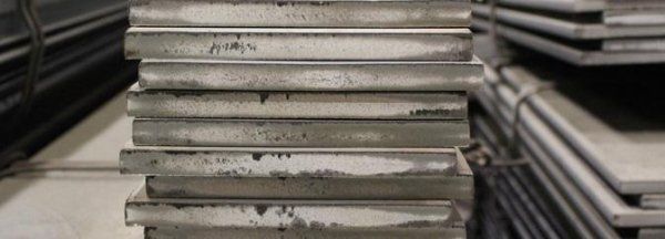 Una pila di piastre metalliche adagiate una sull'altra in un magazzino.