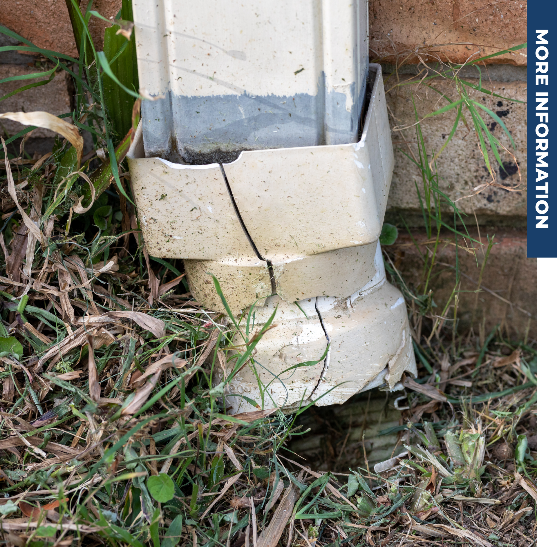 A broken gutter is sitting in the grass next to a brick wall.
