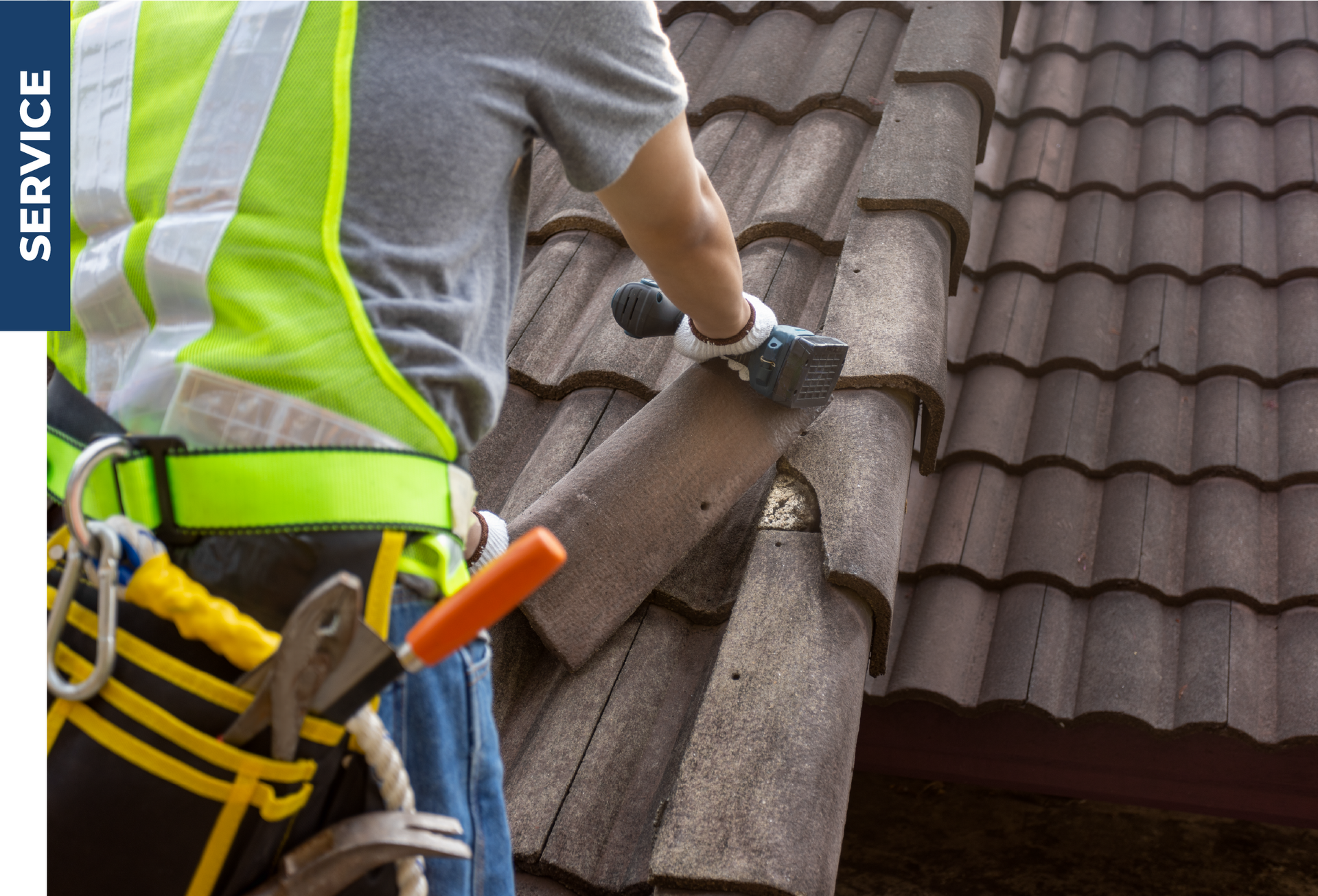 A man wearing a yellow vest is working on a roof