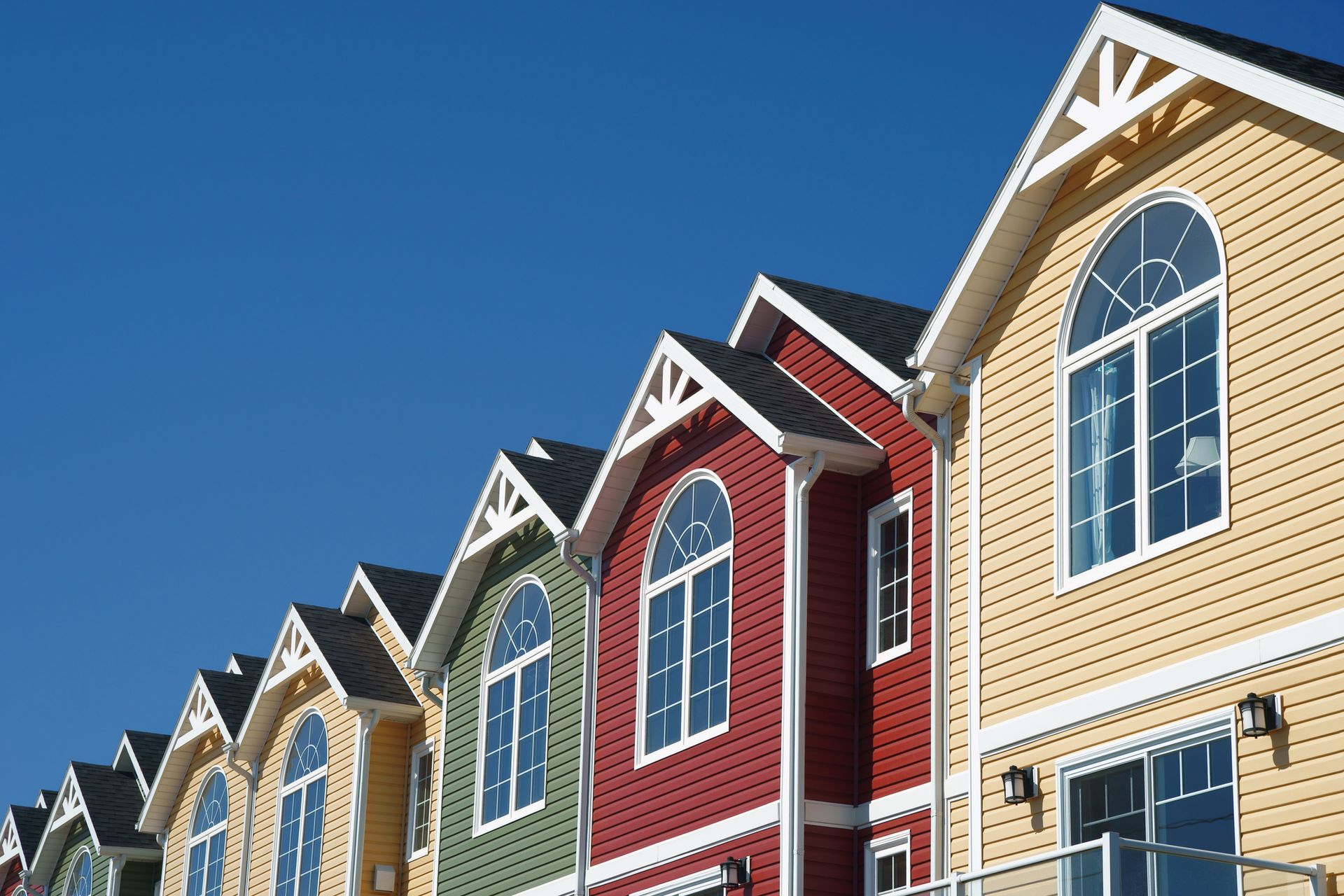 A row of colorful houses with arched windows against a blue sky