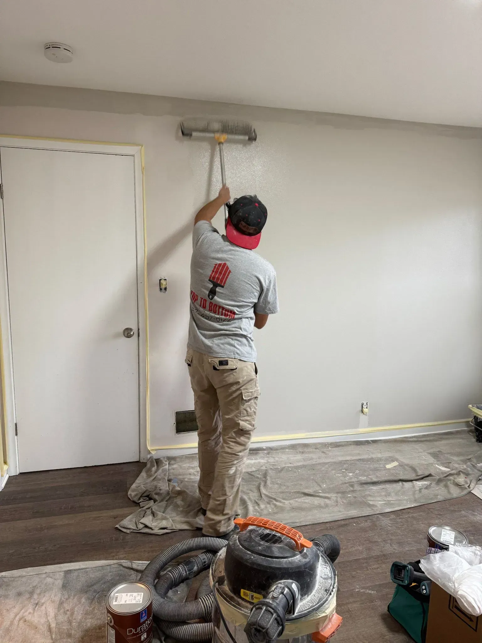 A man is painting a wall in a room with a roller.