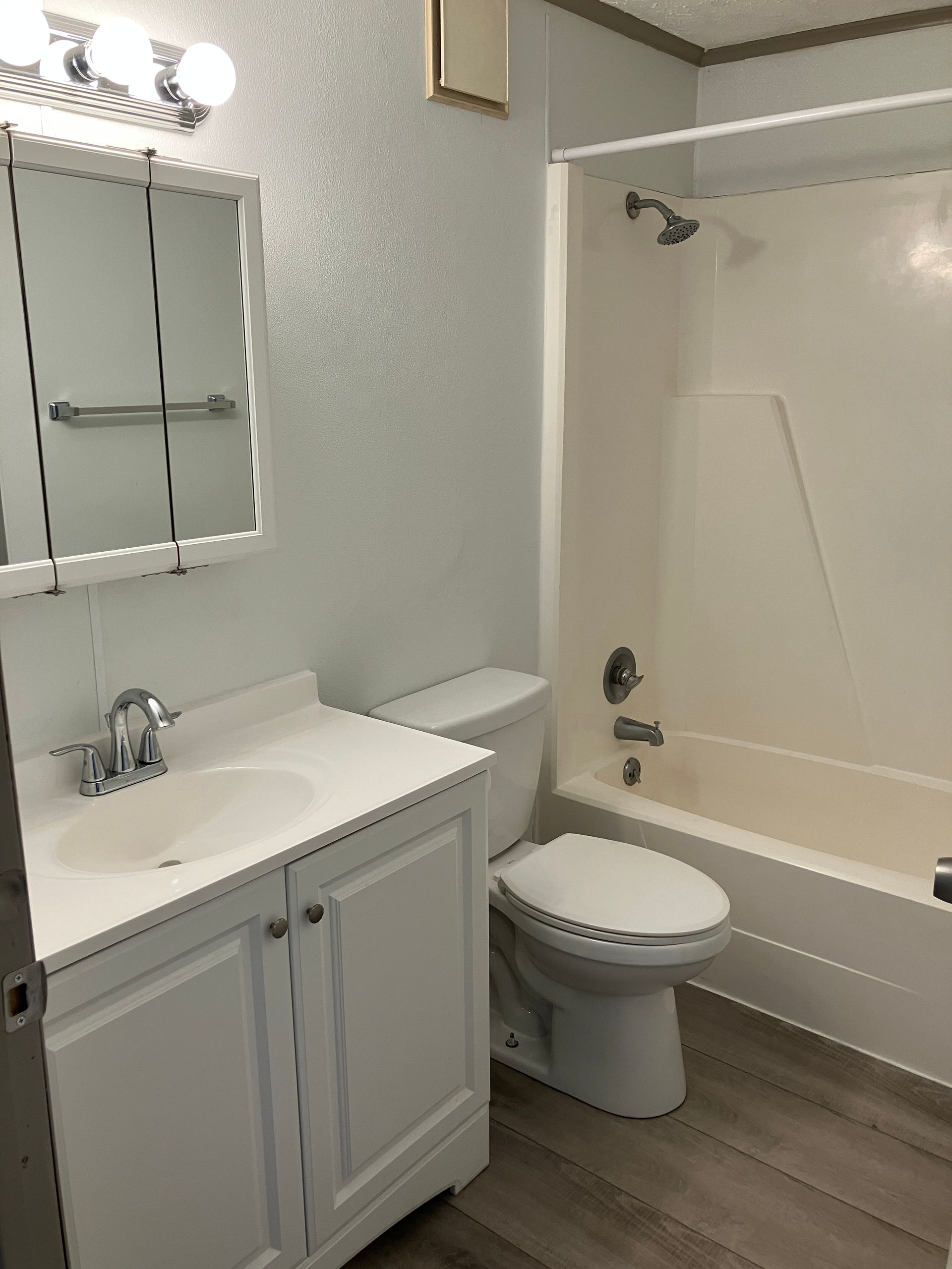 A bathroom with a toilet , sink , bathtub and mirror.
