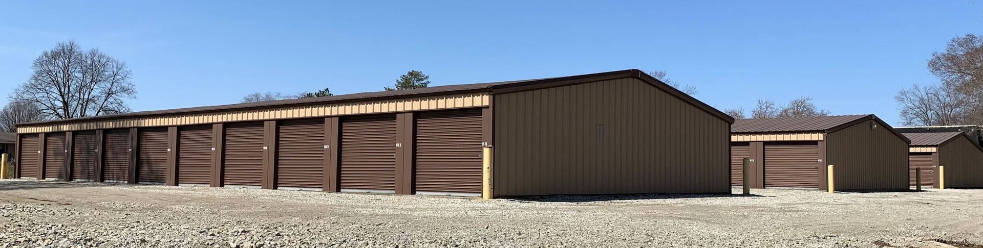 A row of wooden sheds are lined up in a field.