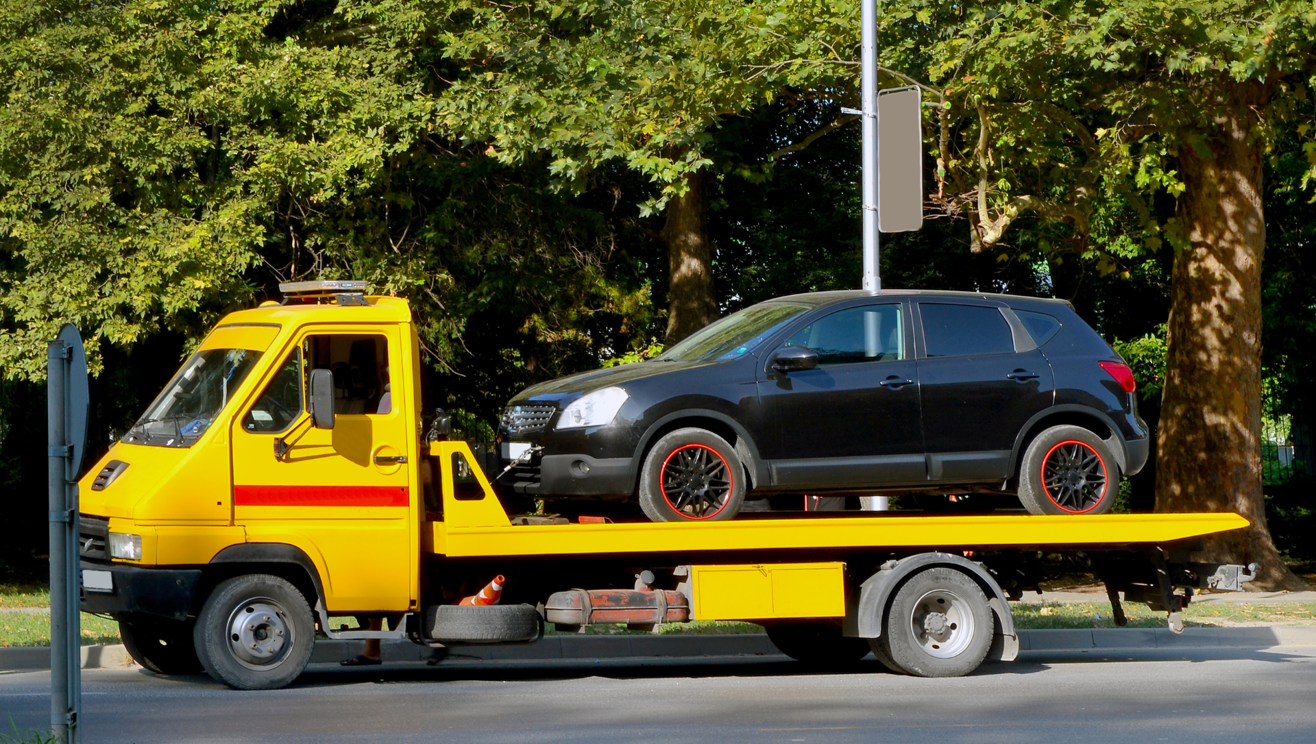 SUV being transported on a yellow flatbed tow truck.