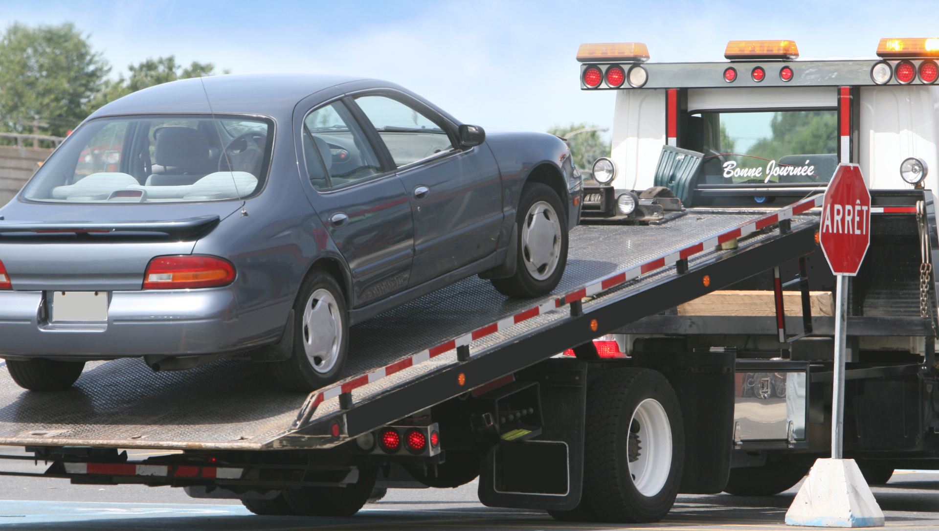 Car being loaded onto a flatbed tow truck.