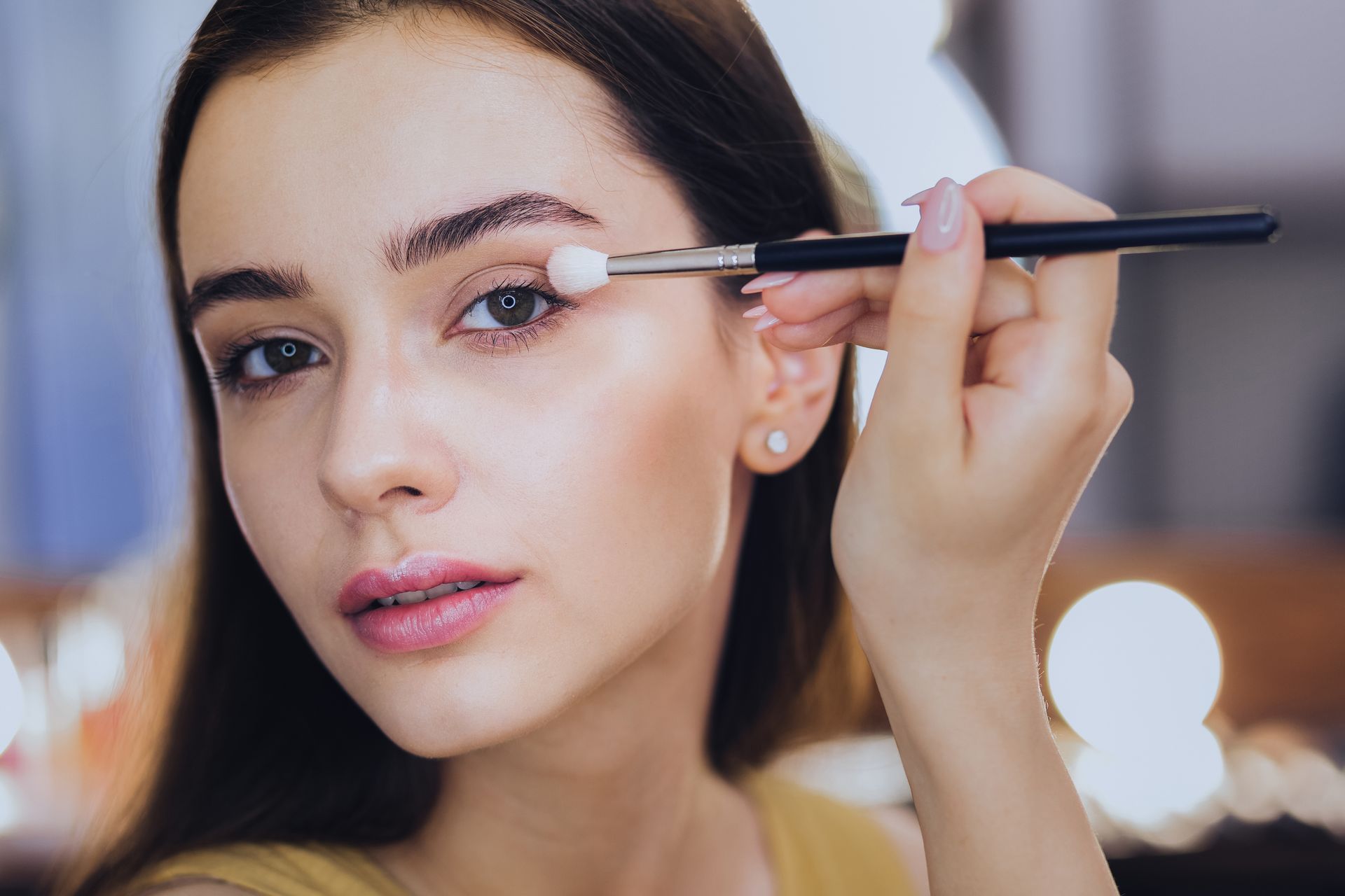 Woman applying eye shadow with a brush; close-up view.