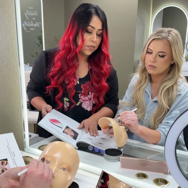 Two women in makeup studio reviewing makeup techniques.