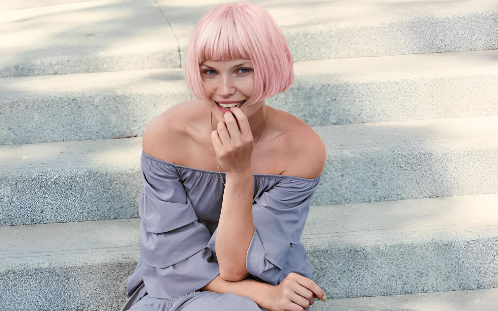 A Woman With Pink Hair is Sitting on a Set of Stairs — Strut Hair & Beauty In Maroochydore, QLD