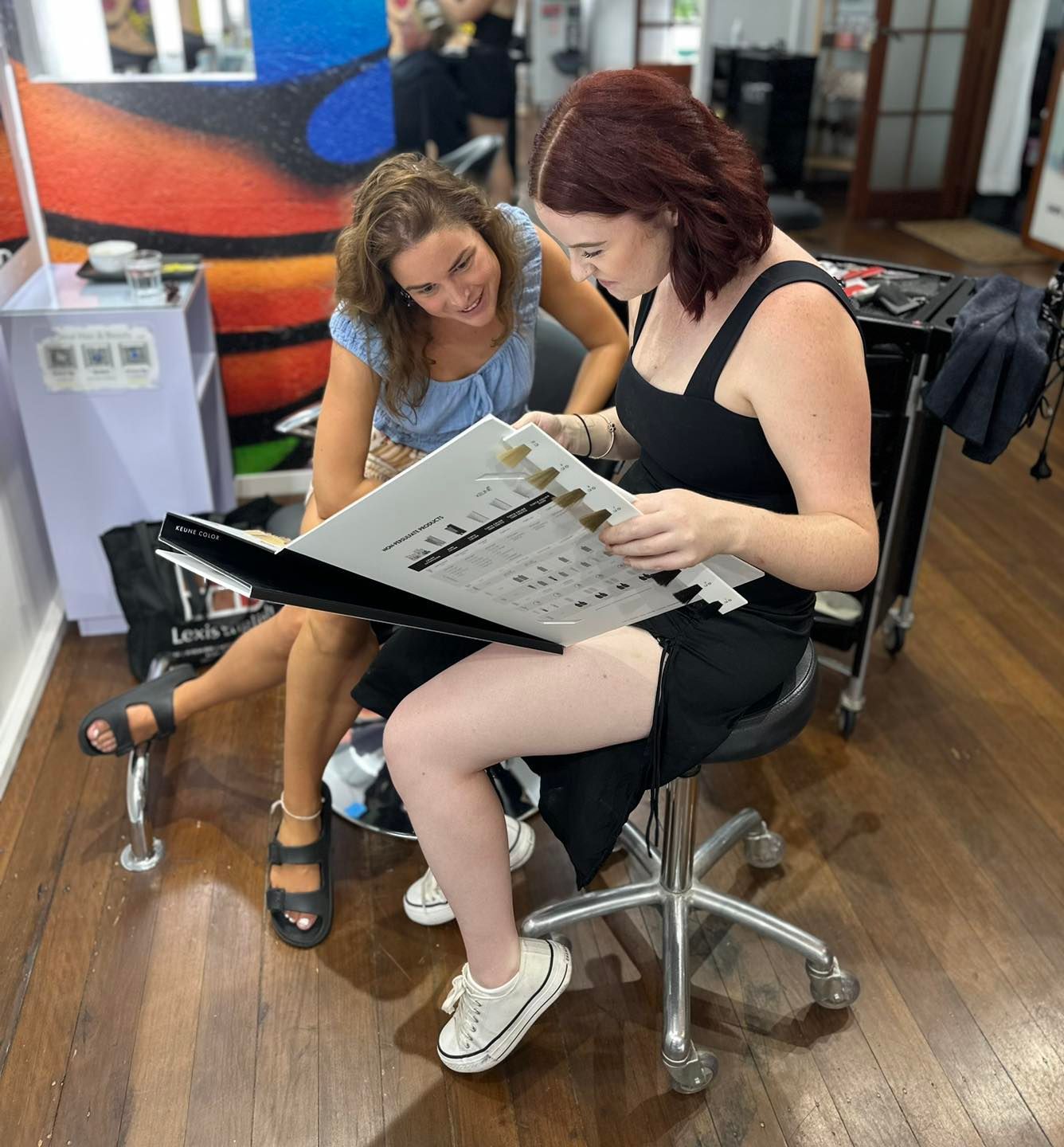 Two women looking at hair color swatches in a salon — Strut Hair & Beauty In Maroochydore, QLD