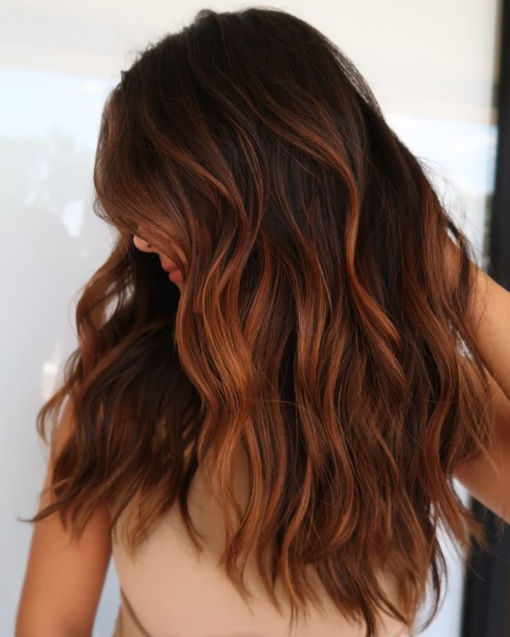 Woman with wavy, dark brown hair with copper highlights — Strut Hair & Beauty In Maroochydore, QLD