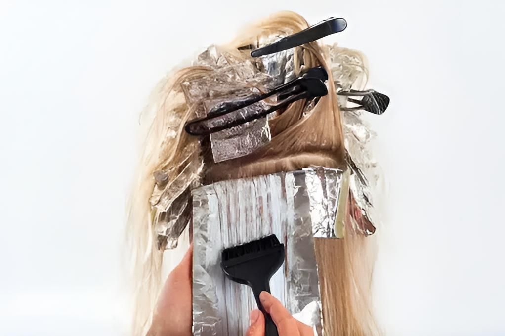 A Woman is Getting Her Hair Dyed With a Brush and Foil — Strut Hair & Beauty In Maroochydore, QLD