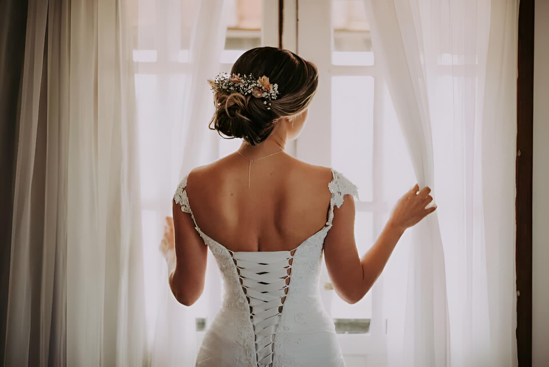 A Bride in a Wedding Dress is Standing in Front of a Window — Strut Hair & Beauty In Maroochydore, QLD