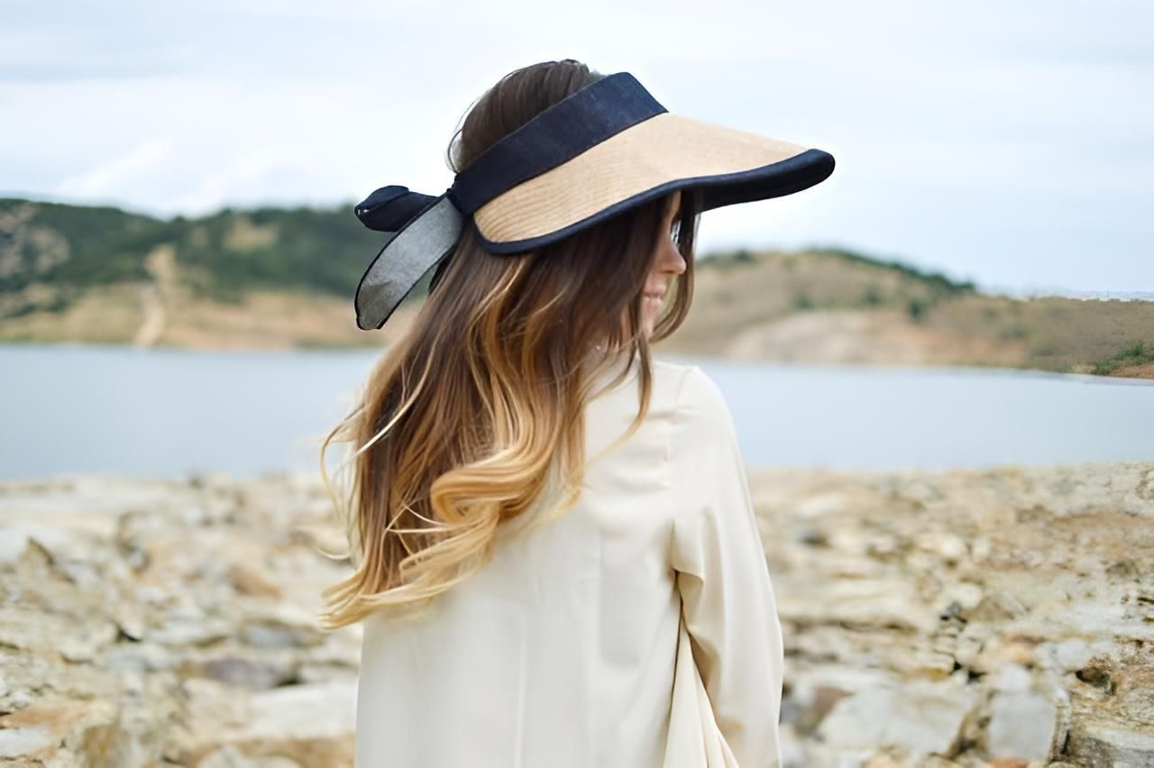 A Woman Wearing a Hat and Sunglasses is Standing on a Rocky Beach — Strut Hair & Beauty In Maroochydore, QLD