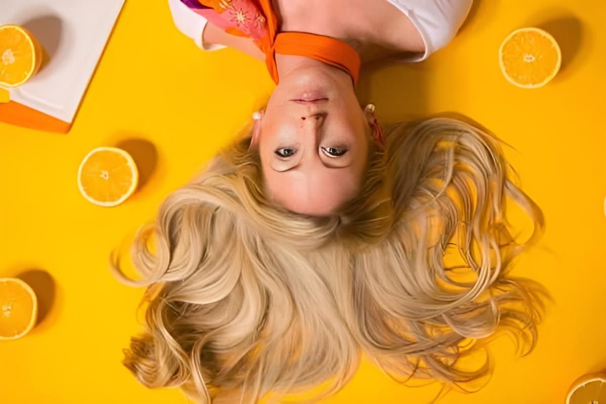 A Woman With a Blonde Hair With Orange Background — Strut Hair & Beauty In Maroochydore, QLD