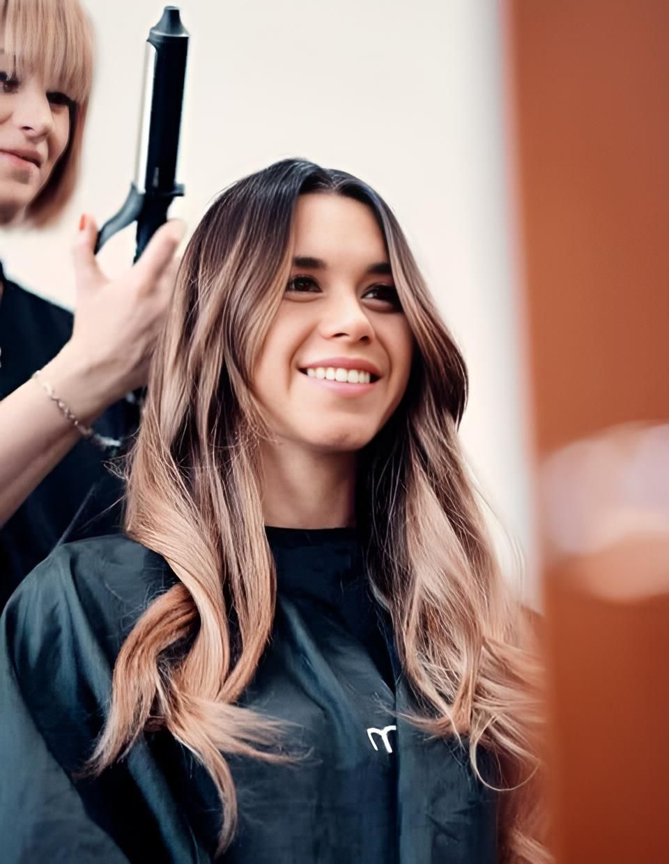 A Woman is Getting Her Hair Done by a Hairdresser and Smiling — Strut Hair & Beauty In Maroochydore, QLD