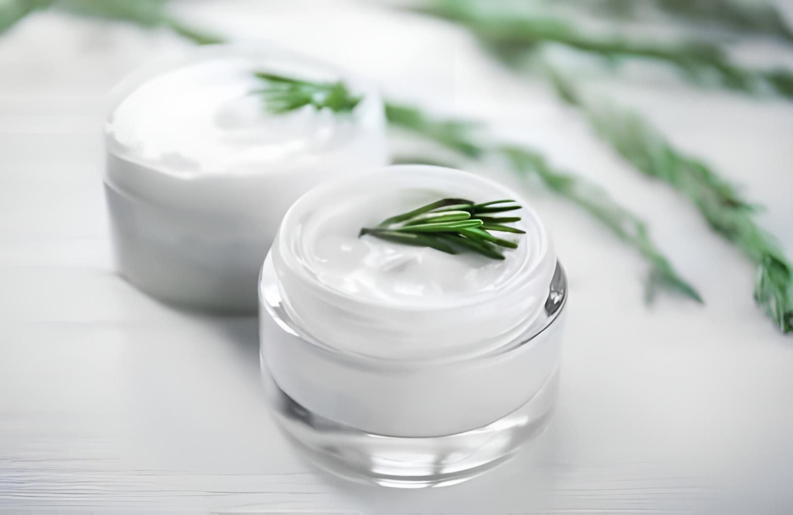 Two Jars of Cream With Rosemary Leaves on a White Table — Strut Hair & Beauty In Maroochydore, QLD