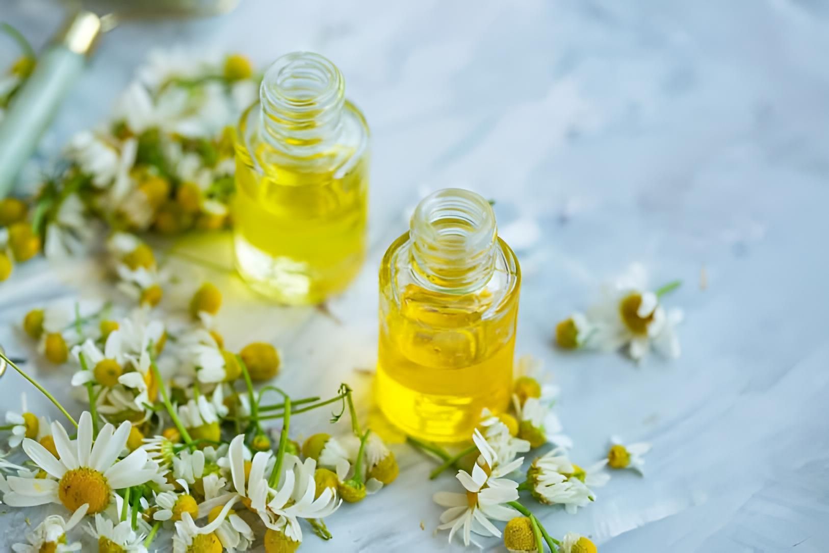 Two Bottles of Essential Oil With Chamomile Flowers on a Table — Strut Hair & Beauty In Maroochydore, QLD