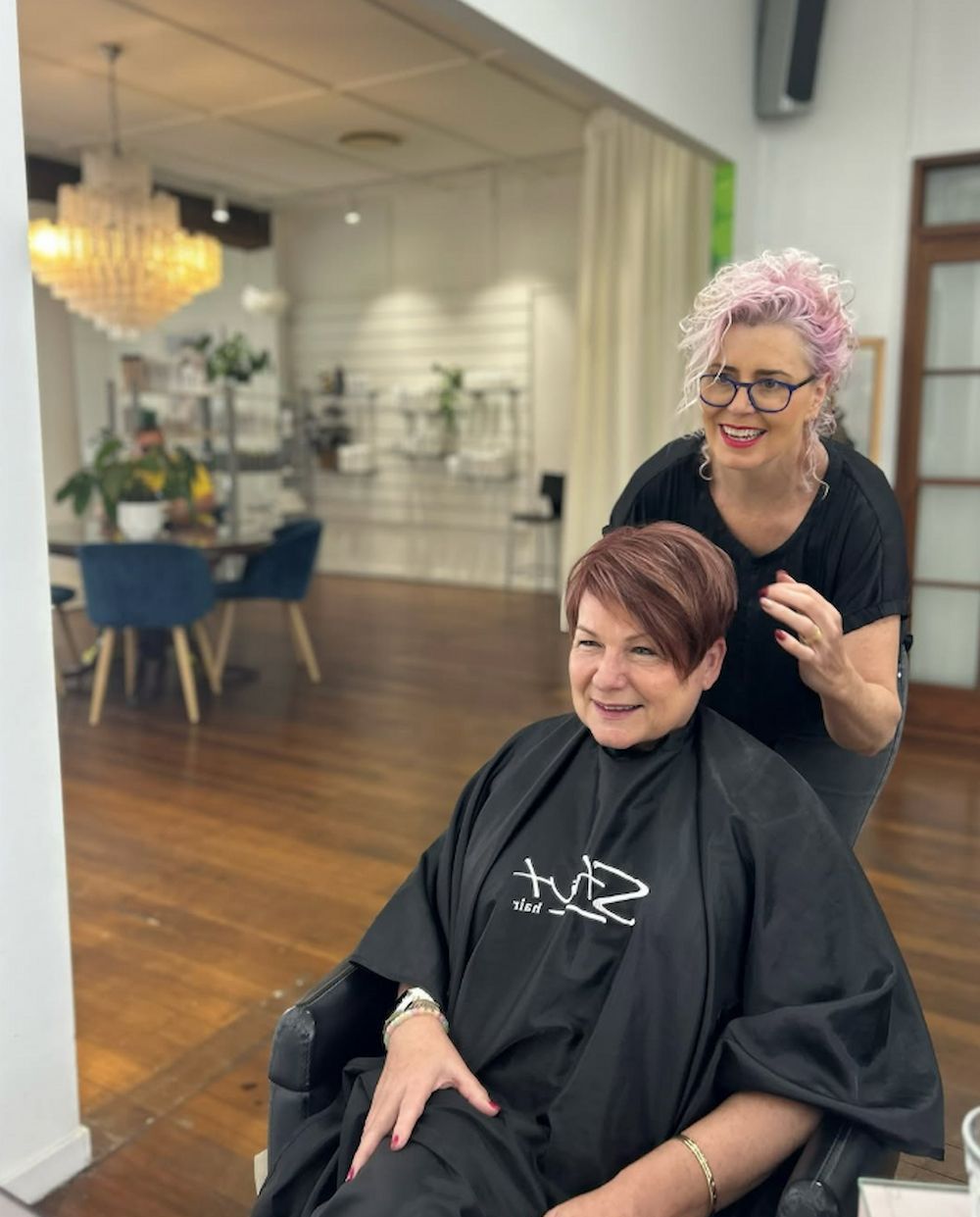 Woman in Salon Chair Smiling, Another Woman With Pink Hair Standing Behind — Strut Hair & Beauty In Maroochydore, QLD