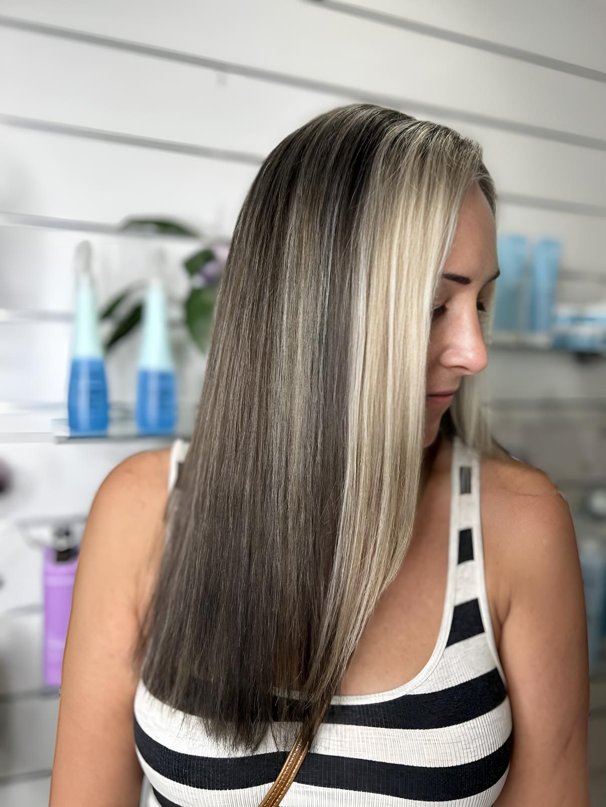 A Woman With Long Blonde Hair is Wearing a Striped Tank Top — Strut Hair & Beauty In Maroochydore, QLD