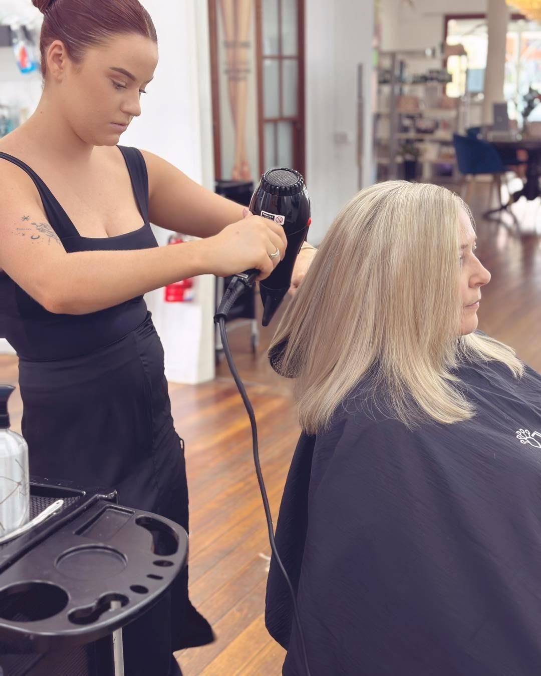 A Woman is Getting Her Hair Blow Dried in a Salon — Strut Hair & Beauty In Maroochydore, QLD