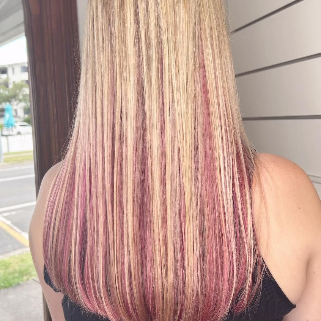 A Woman With Blonde and Pink Hair is Standing in Front of a Building — Strut Hair & Beauty In Maroochydore, QLD