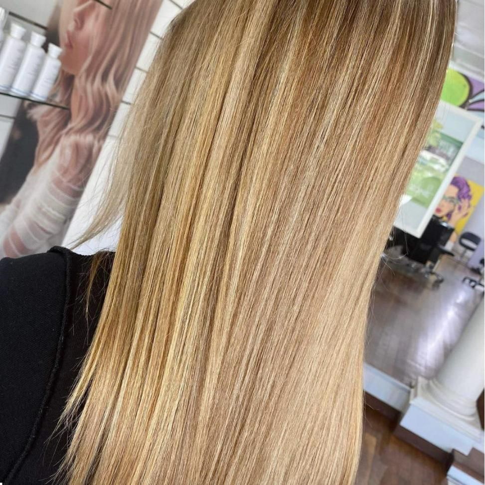 A Woman With Long Blonde Hair is Standing in a Salon — Strut Hair & Beauty In Maroochydore, QLD