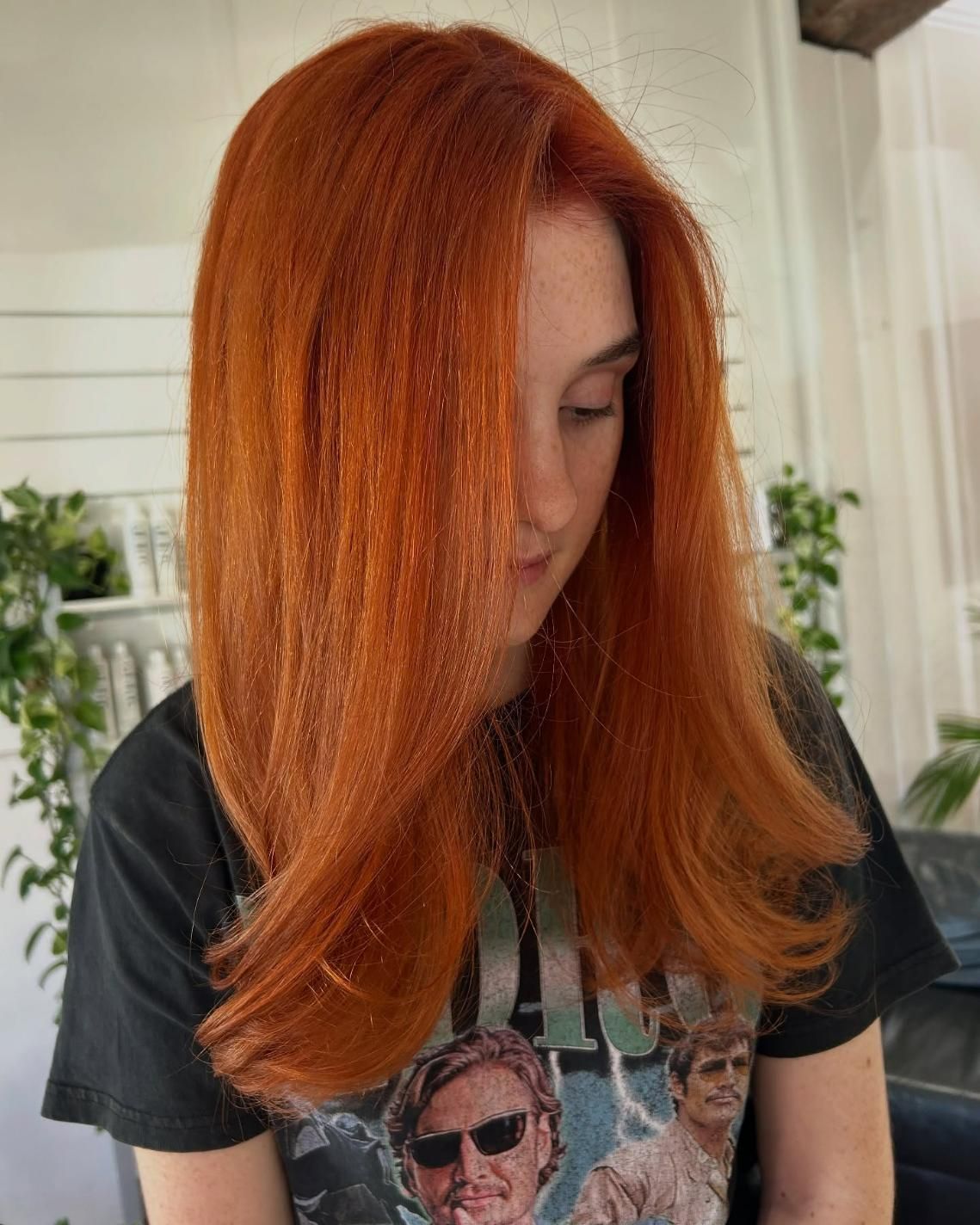A Woman With Red Hair is Wearing a Black T-shirt With a Picture of a Man on It — Strut Hair & Beauty In Maroochydore, QLD