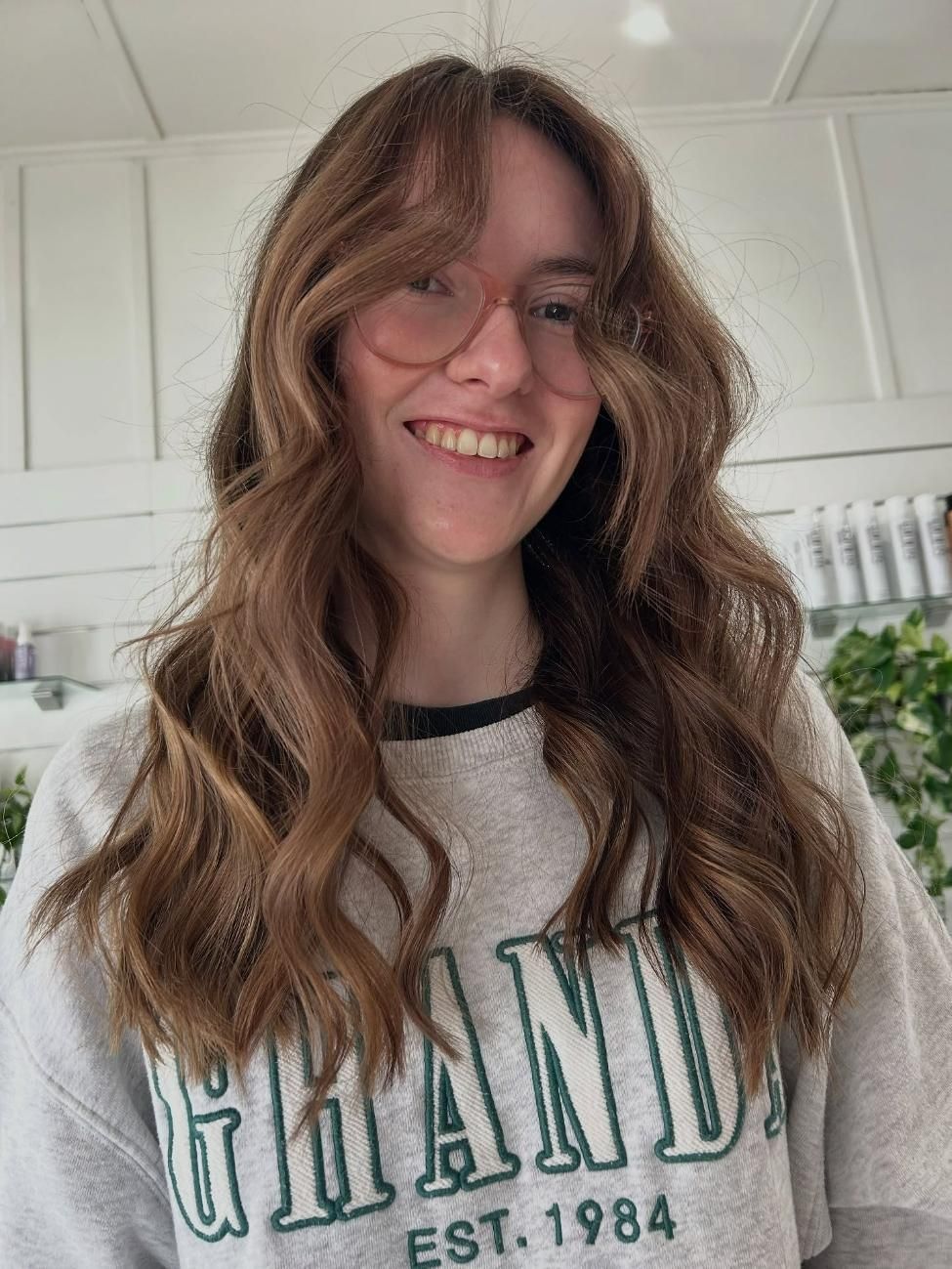 A Woman Wearing Glasses and a Sweatshirt With the Word Grand on It is Smiling — Strut Hair & Beauty In Maroochydore, QLD