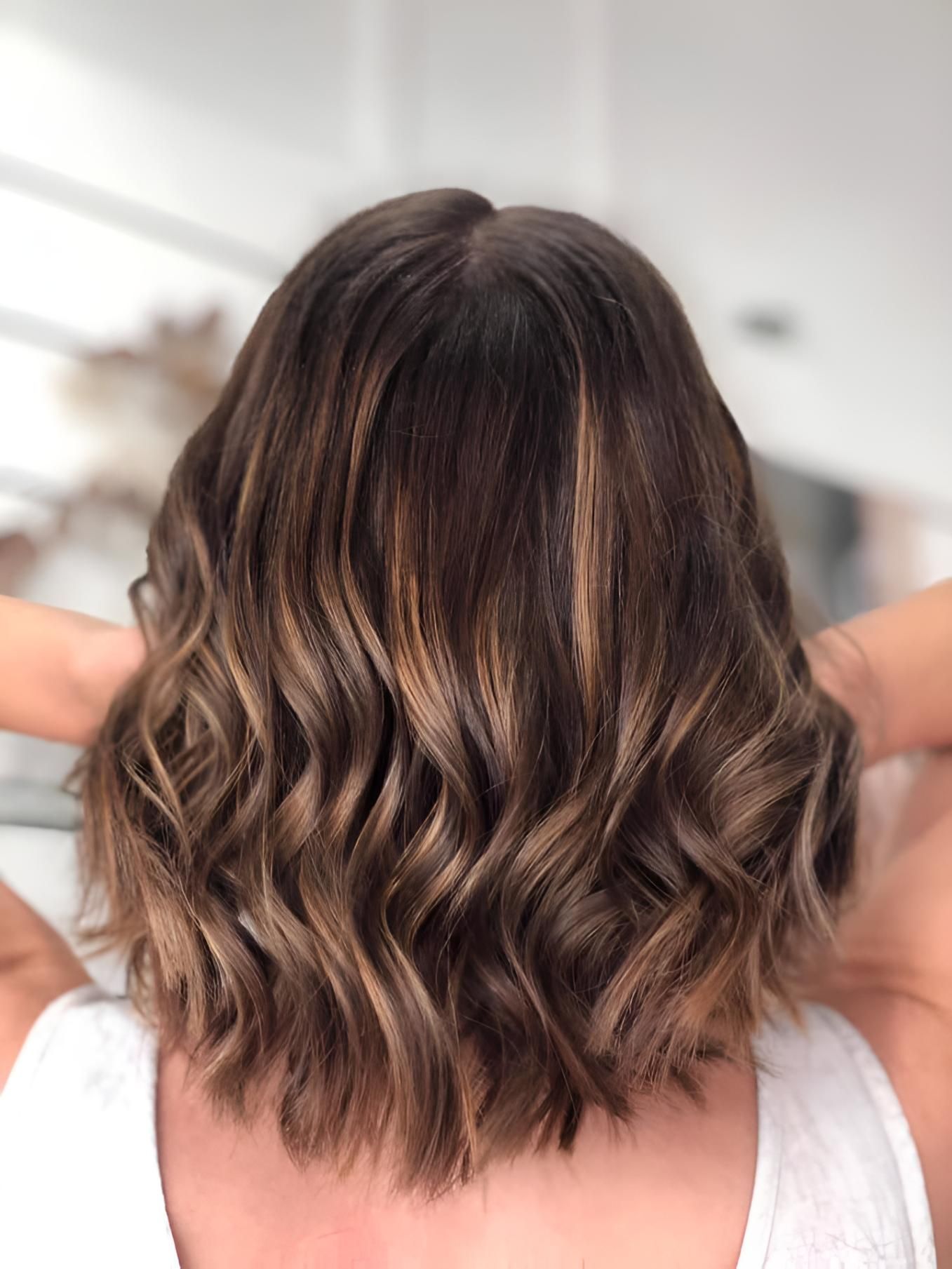A Woman With Short Wavy Brown Hair is Wearing a White Tank Top — Strut Hair & Beauty In Maroochydore, QLD