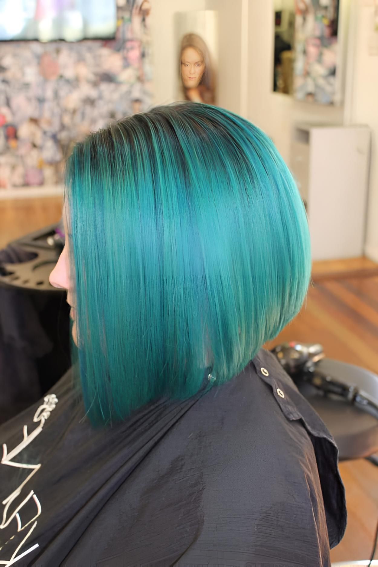 A Woman With Green Hair is Sitting in a Chair in a Salon — Strut Hair & Beauty In Maroochydore, QLD