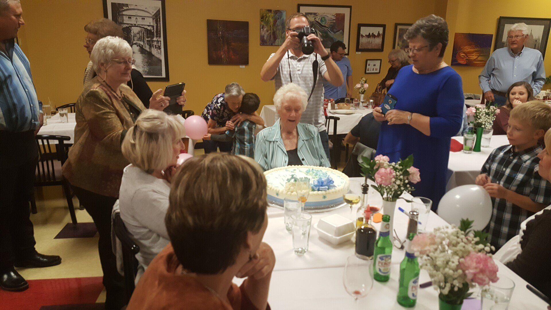 a group of people are sitting around a table with a cake on it .