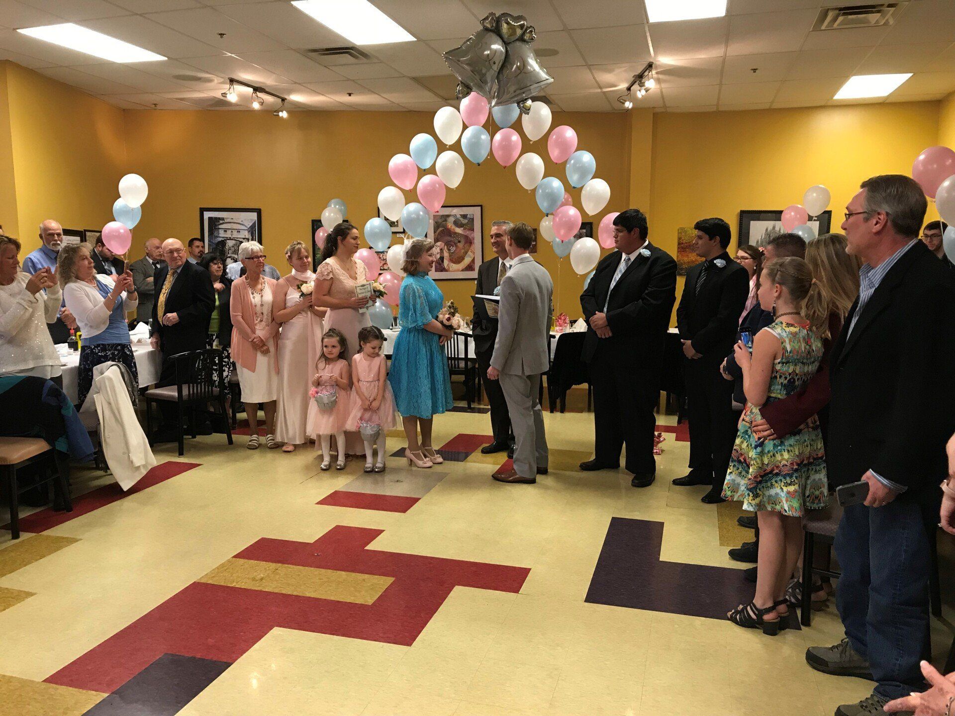a group of people are standing in a room with balloons .