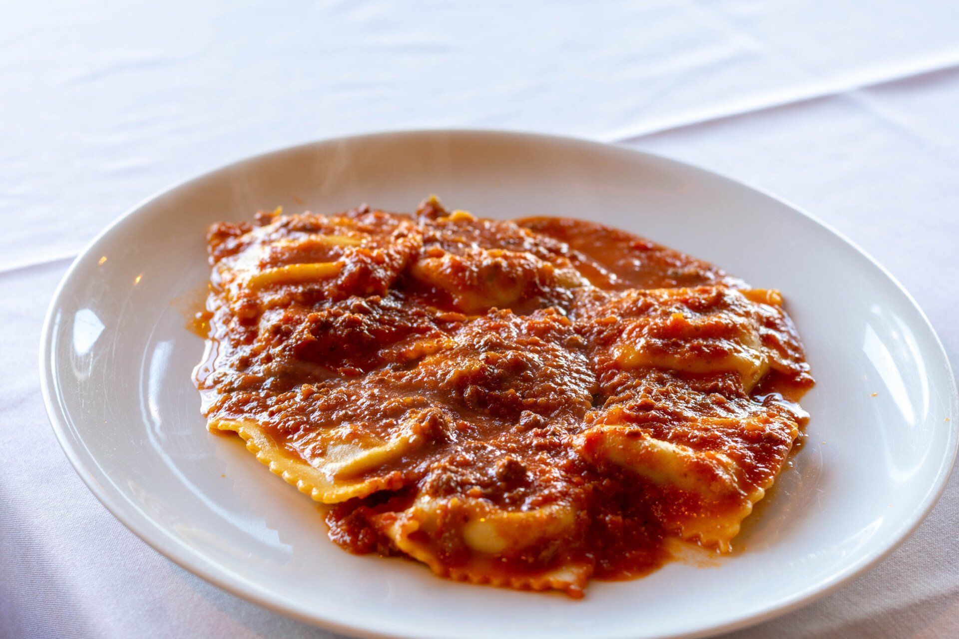 a white plate topped with ravioli and sauce on a table .