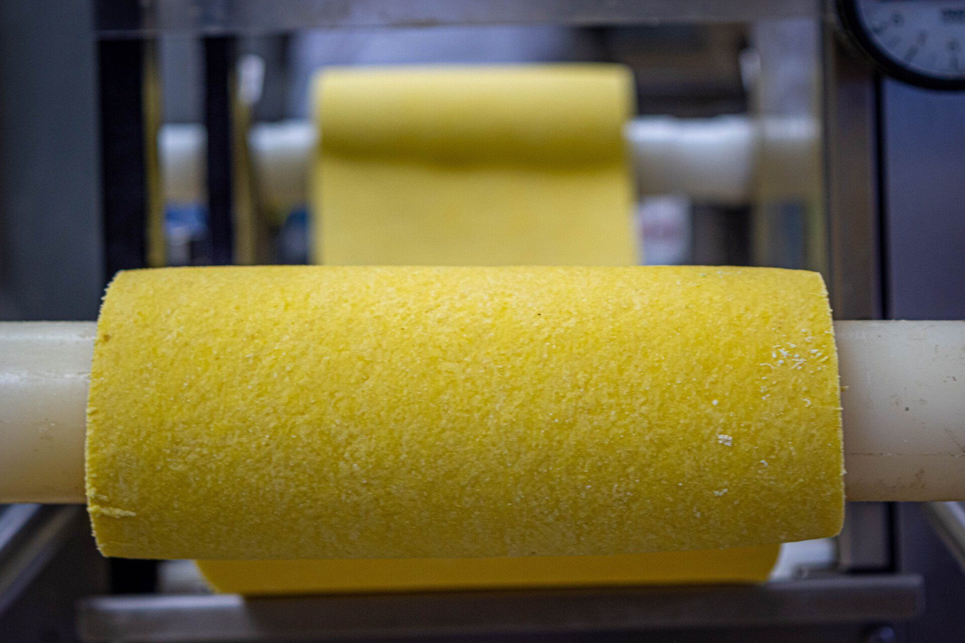 a roll of yellow pasta is being made on a machine