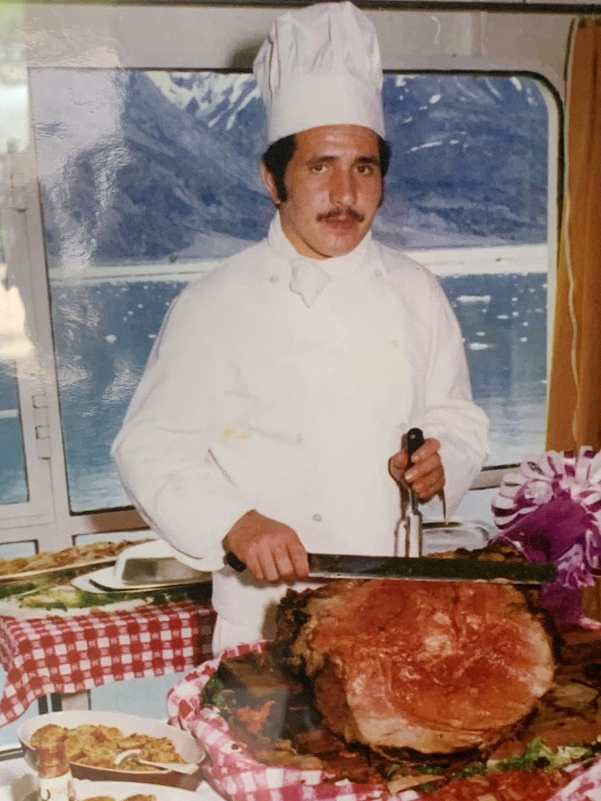 a man in a chef 's hat is cutting a large piece of meat