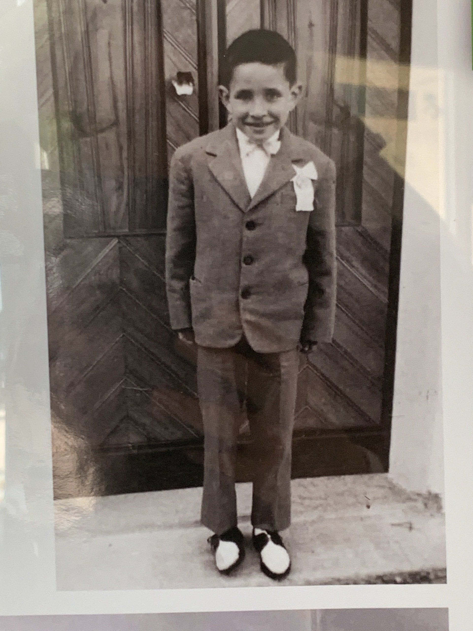 a black and white photo of a young boy in a suit and bow tie