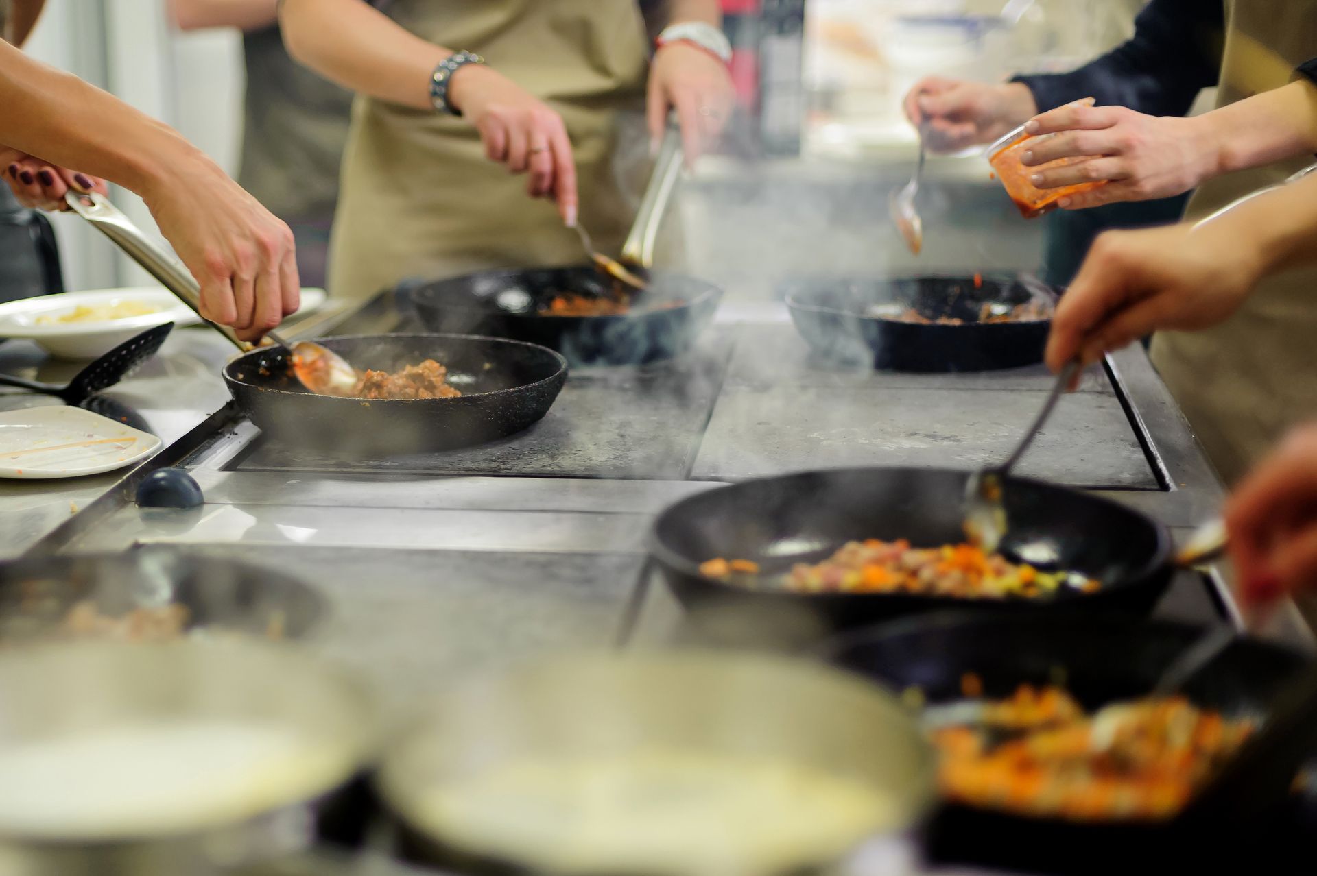 a group of people are cooking food in pans in a kitchen