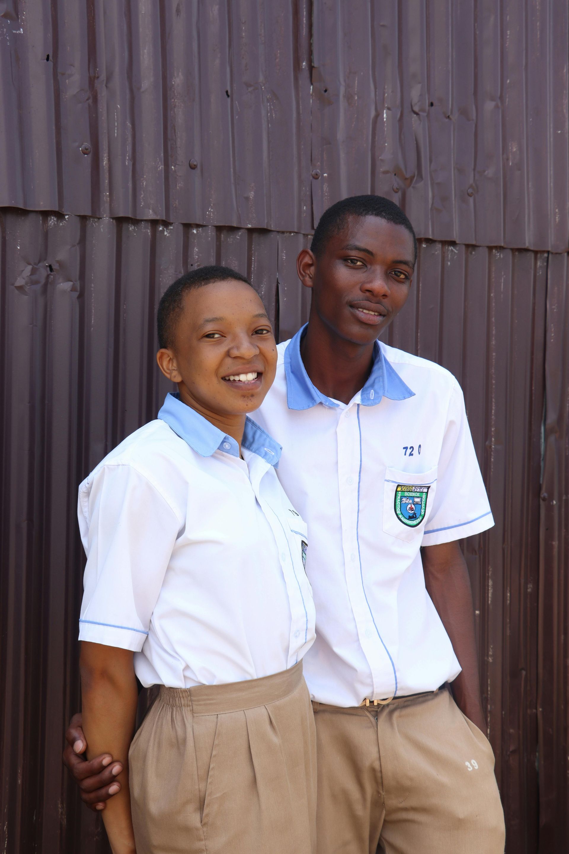 Um menino e uma menina estão posando para uma foto em frente a uma parede de madeira