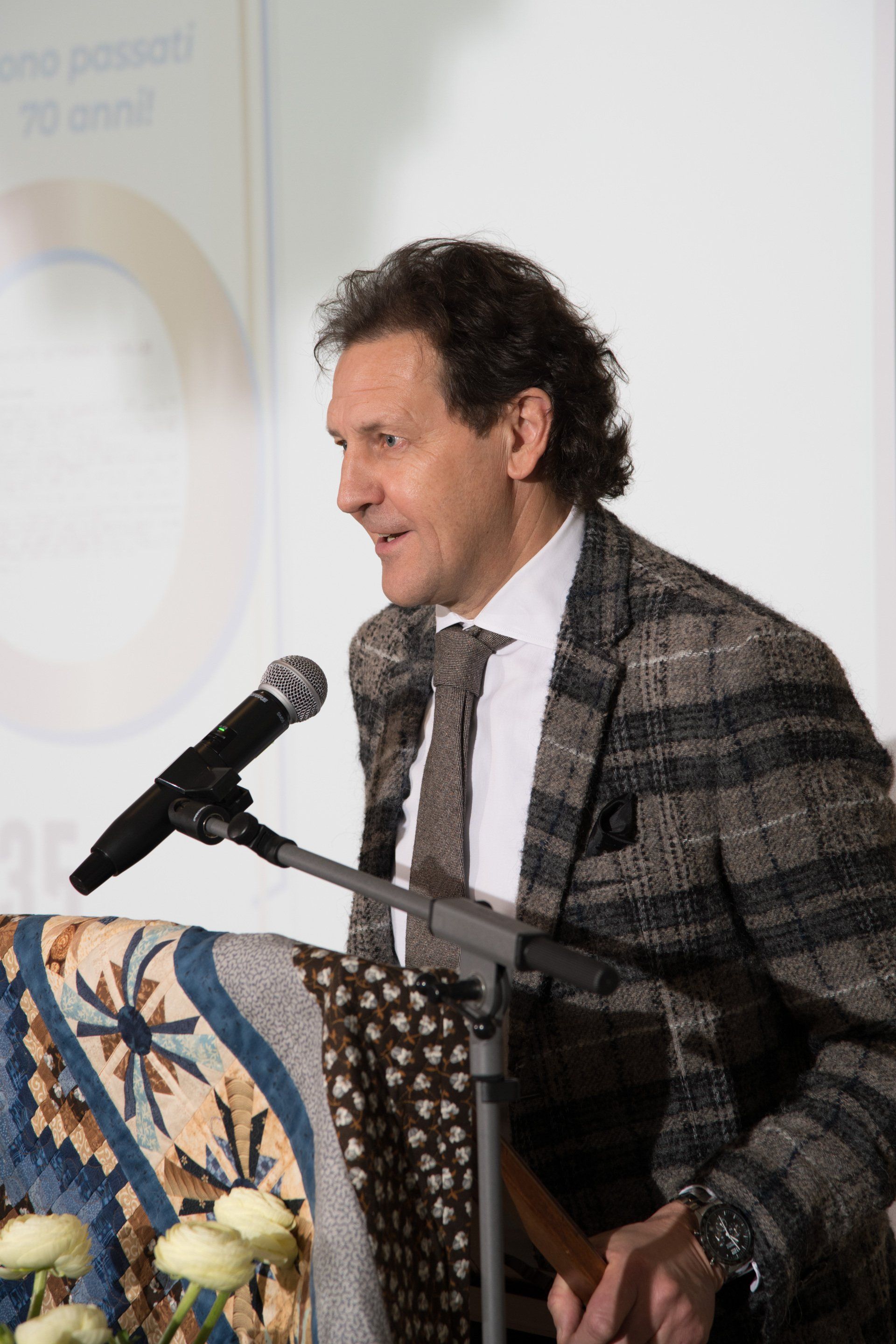 Un uomo in giacca e cravatta parla al microfono.