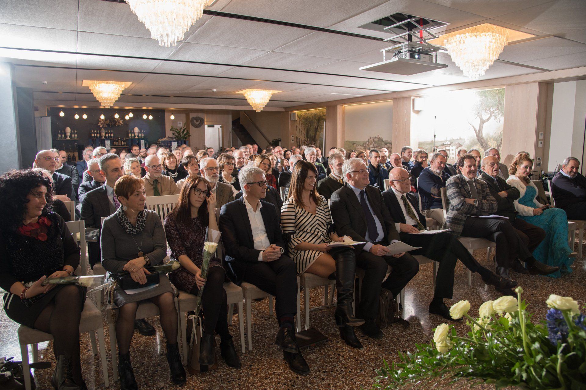 Un folto gruppo di persone è seduto sulle sedie in una stanza.