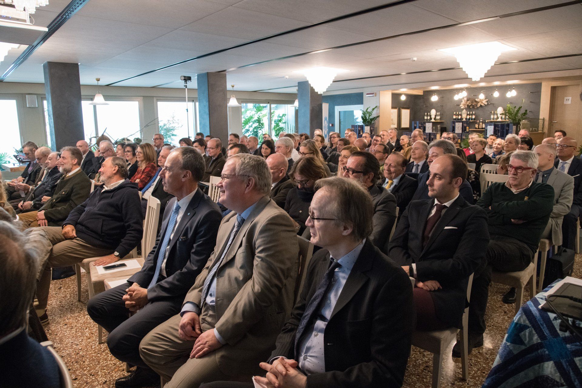 Un folto gruppo di persone è seduto sulle sedie in una stanza.