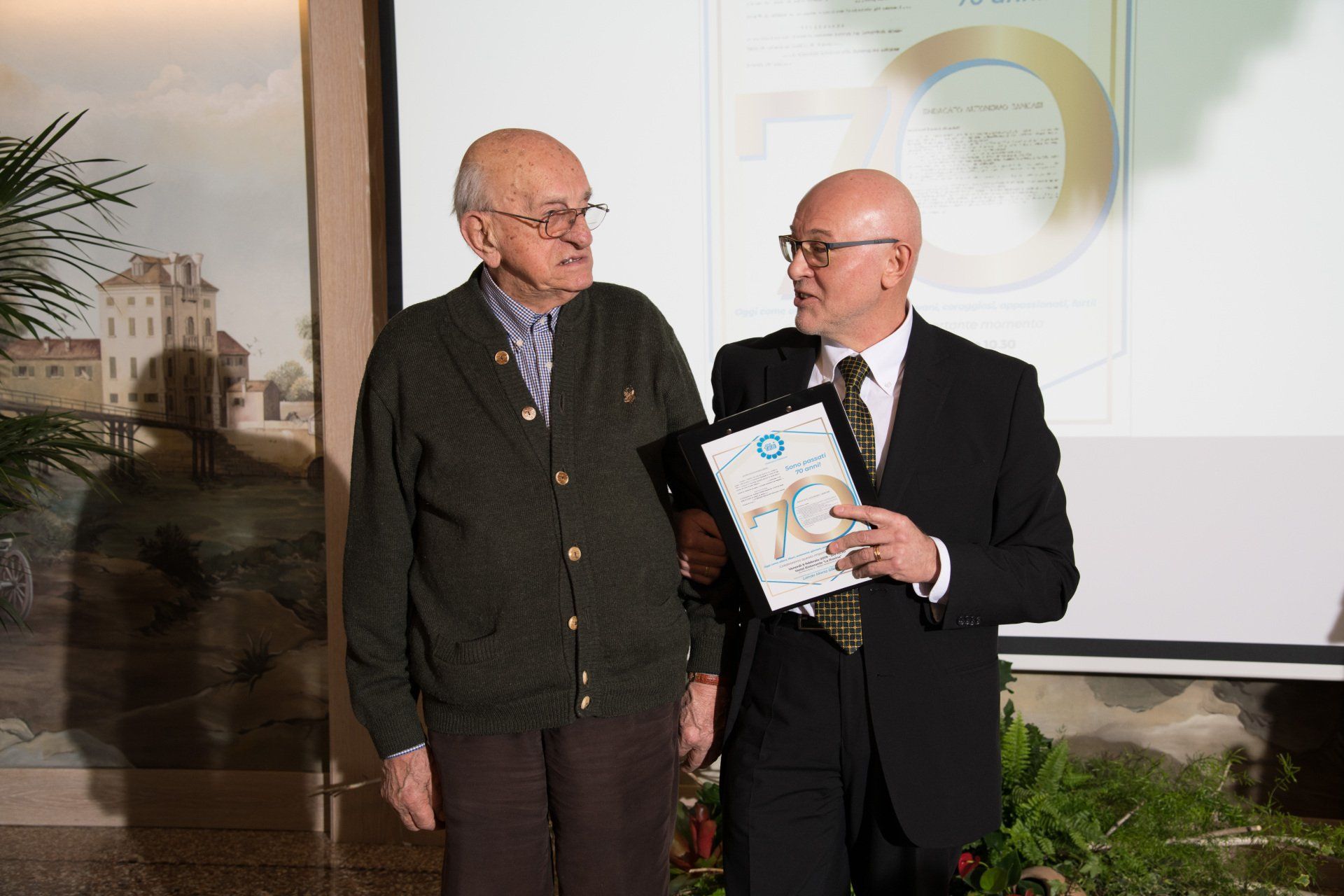 Due uomini sono in piedi uno accanto all'altro e uno ha in mano un certificato