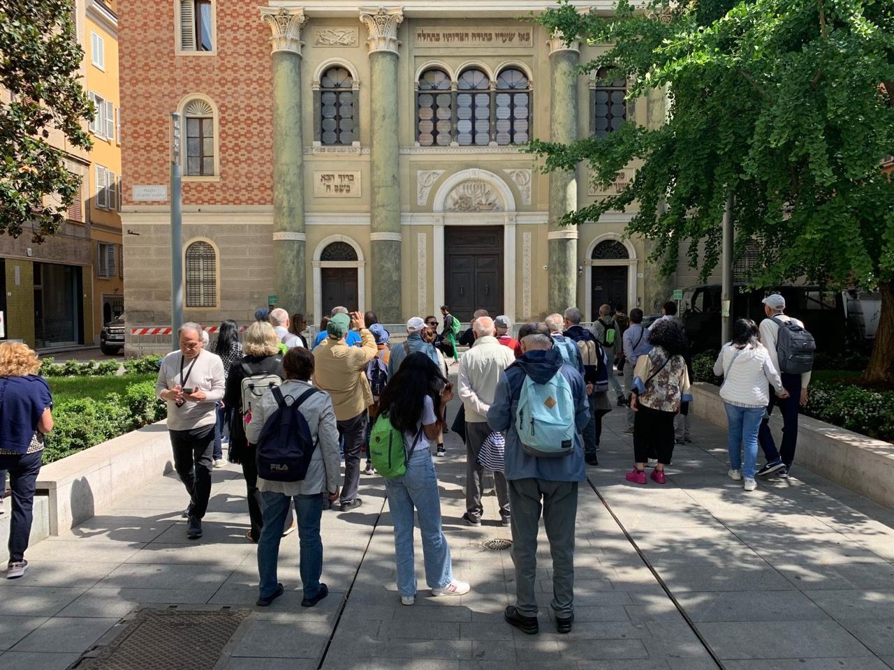 Un gruppo di persone cammina sul marciapiede davanti a un edificio.