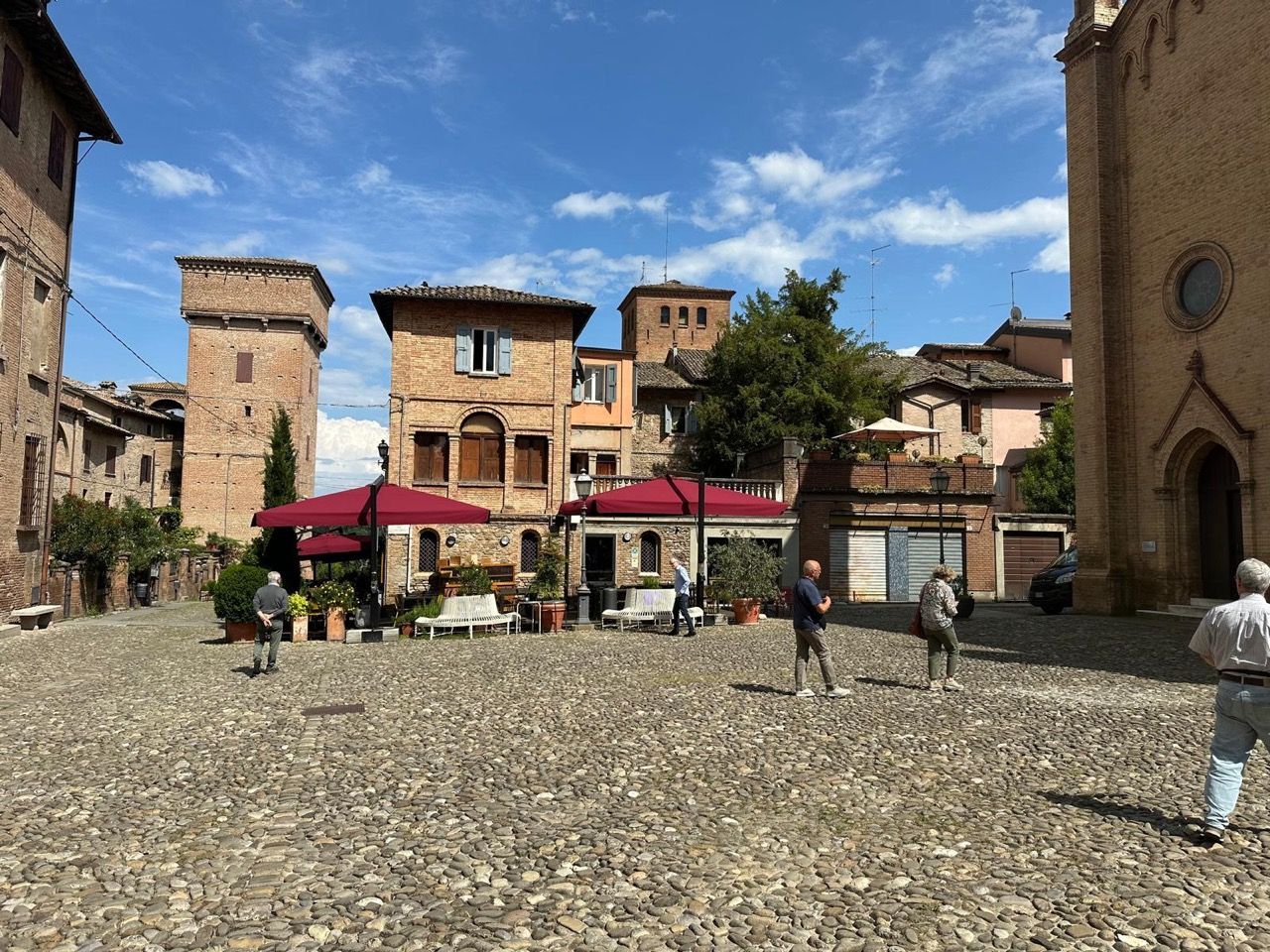 Un gruppo di persone è in piedi in una piazza acciottolata di fronte a una chiesa.