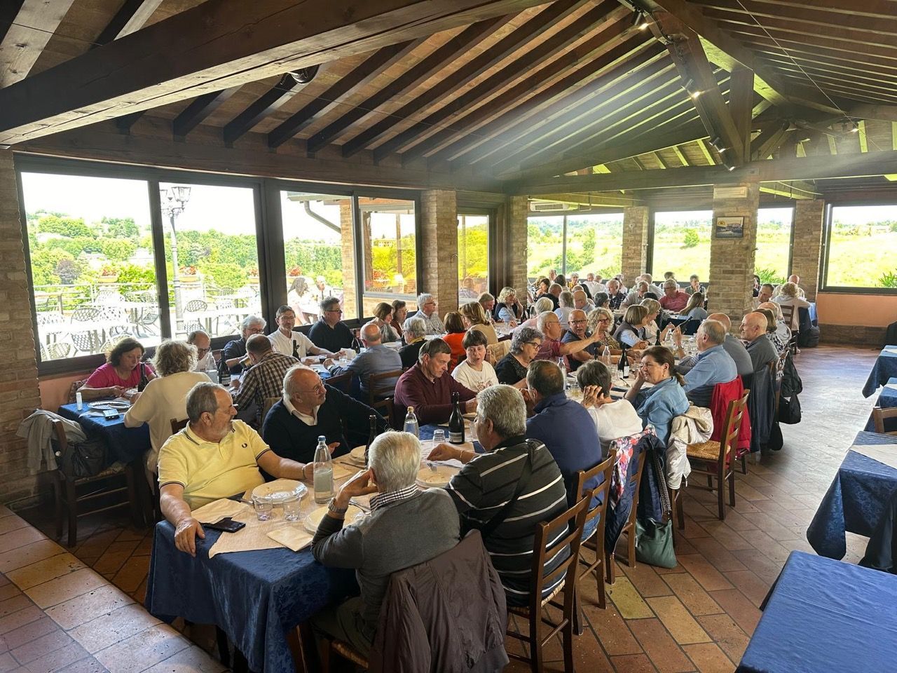 Un folto gruppo di persone è seduto ai tavoli di un ristorante.