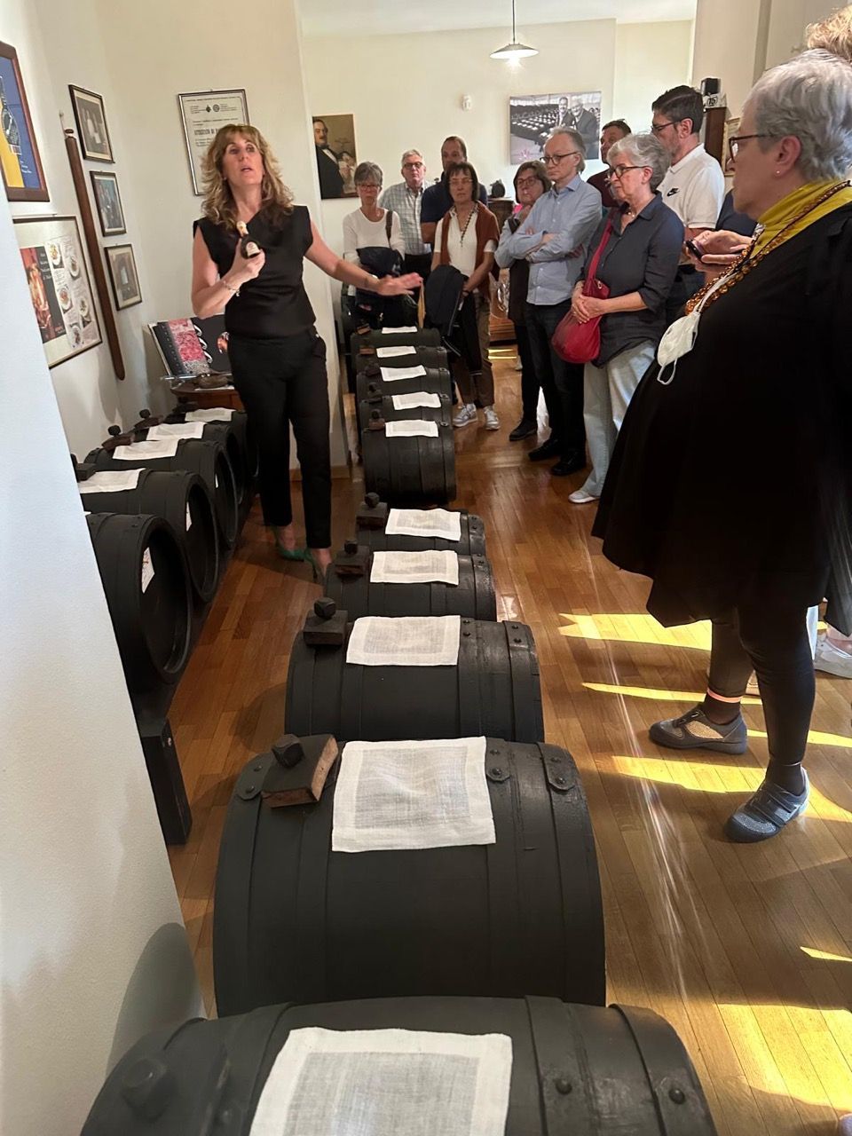 Un gruppo di persone è in piedi attorno a una fila di barili in una stanza.