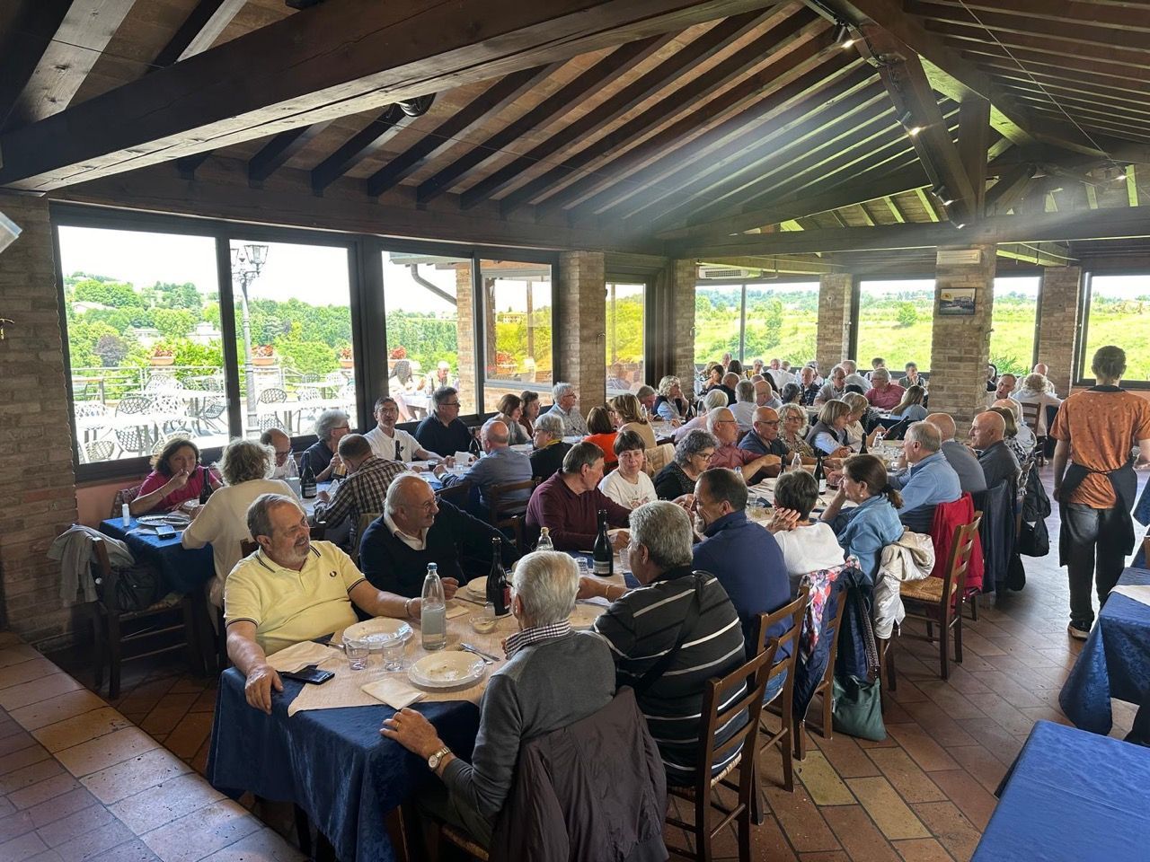 Un folto gruppo di persone è seduto ai tavoli di un ristorante.