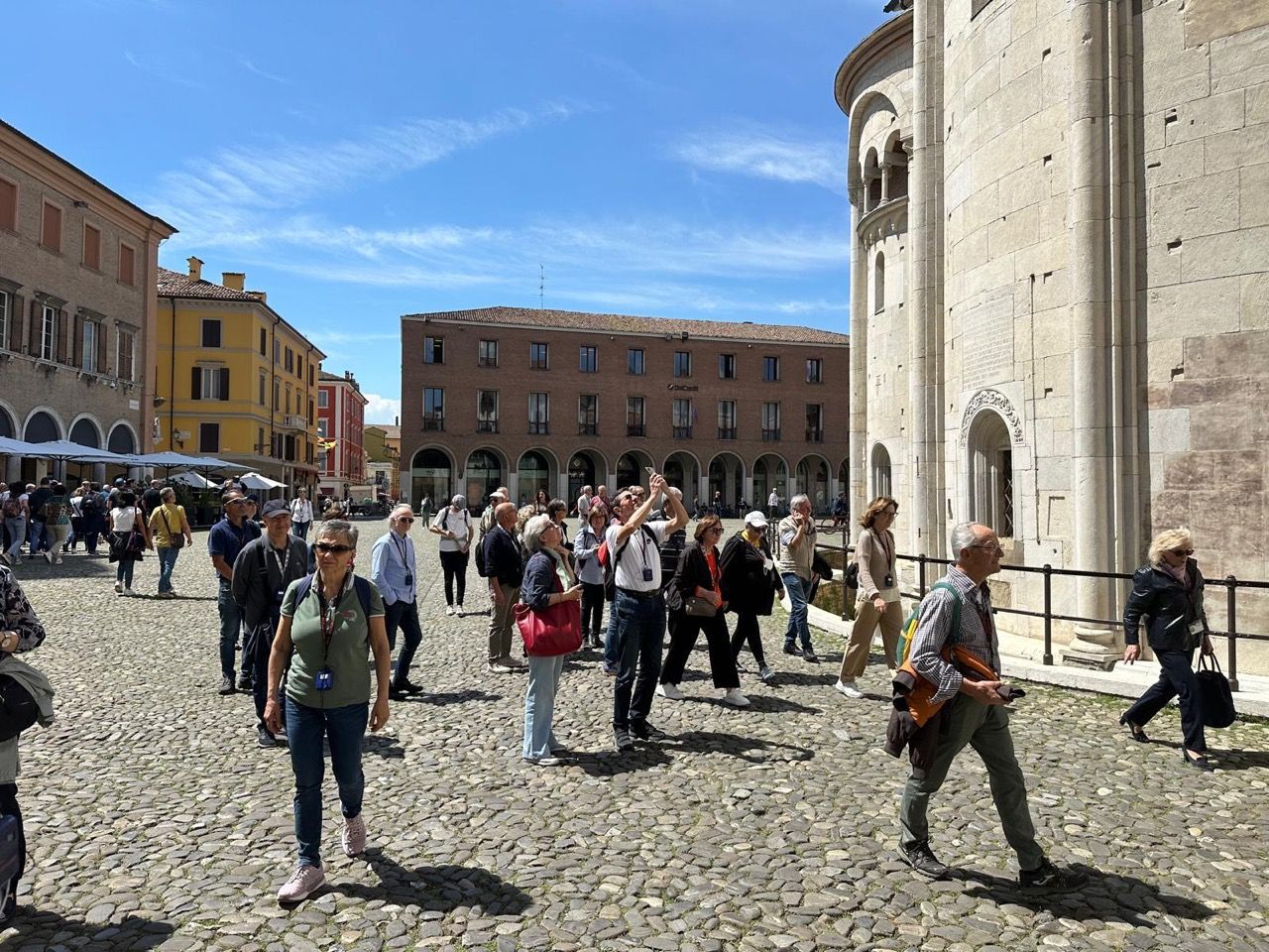 Un gruppo di persone cammina lungo una strada acciottolata davanti a un edificio.