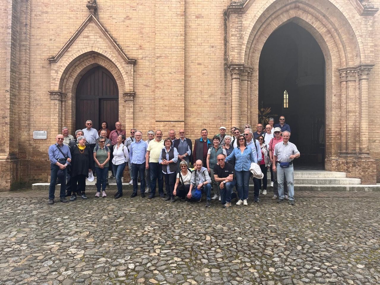 Un gruppo di persone posa per una foto davanti a una chiesa.